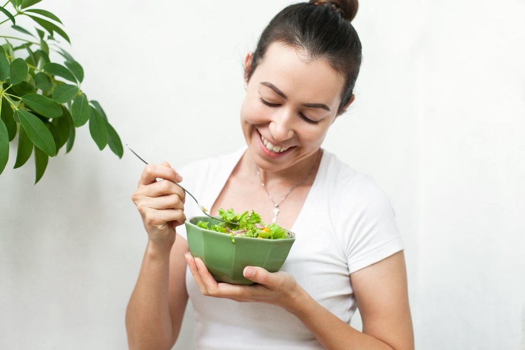 A young woman eating a salad; eating healthy, green diet, vegan, vegetarian, eating veggies, health
