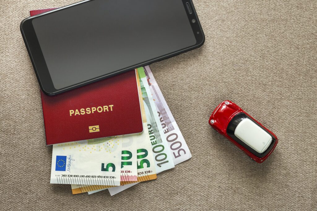 Black cellphone, money euro banknotes bills, passport and toy car
