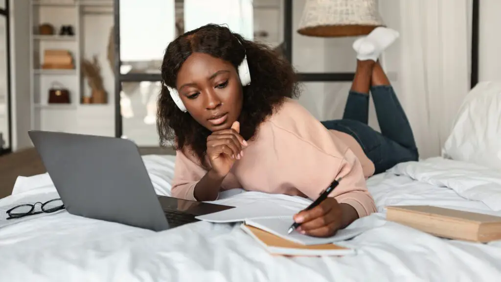 Black Woman Learning Using Laptop Taking Notes At Home