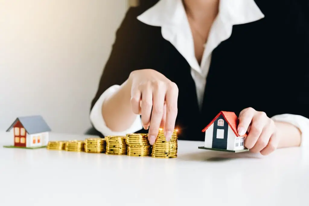 Businesswoman is holding house models and coins concept of Real Estate, home loan, installment loan