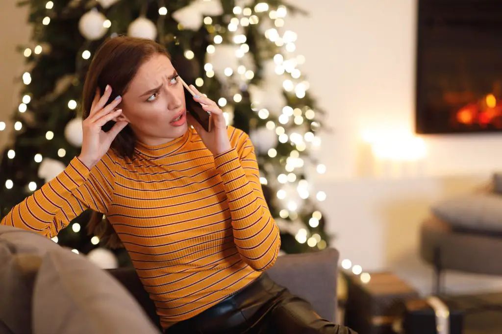 Confused lady talking on cellphone sitting on couch