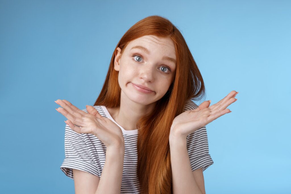 Unsure clueless cute silly redhead female part-time worker shrugging careless raise hands unaware