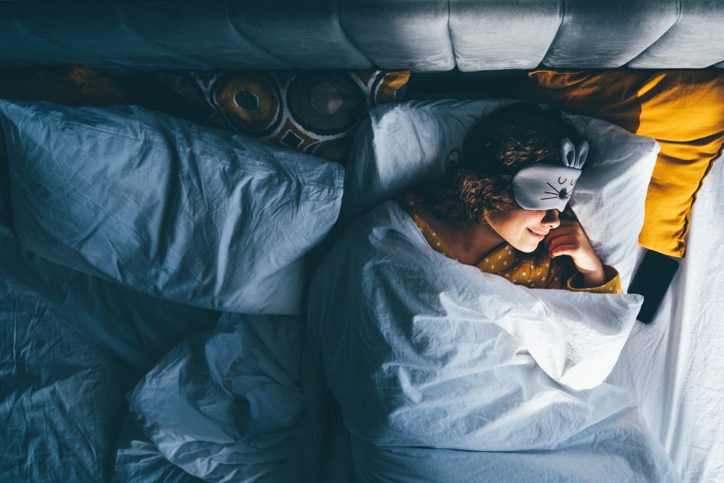 Woman sleeping with a sleep mask on her eyes.