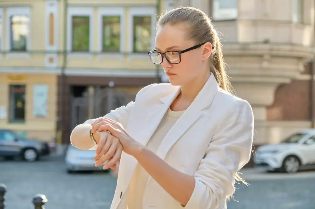Young successful business woman looking at her wristwatch