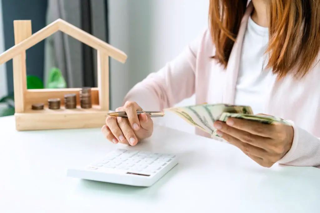 Young woman calculating home expenses with stack of coins