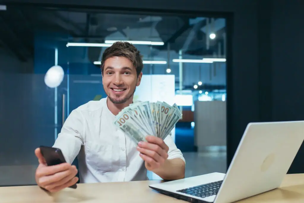 Happy and satisfied young handsome man. Businessman holding a wad of money
