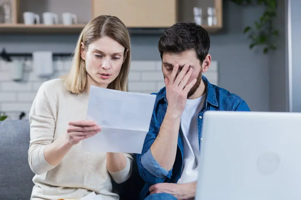 Man and woman, young family together intently reading a letter, frustrated