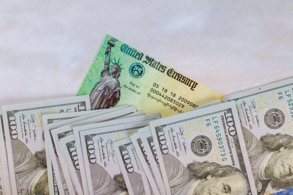 Stimulus economic tax return check and USA currency hundred US dollar bills 1040 U