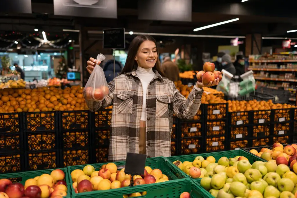 Woman in the fruit department of a grocery supermarket buys apples